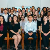 Large corporate group photo with diverse professionals arranged in rows in modern office conference room