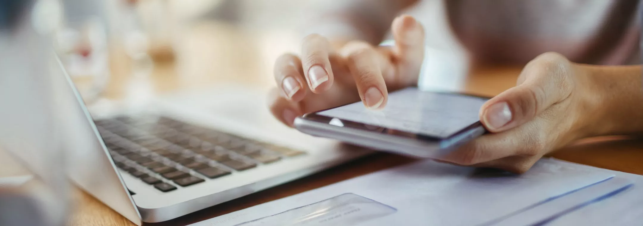 Person reviewing Uplight app on phone with laptop in view.