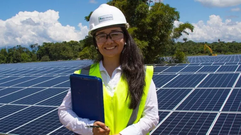 tech - smiling woman in hard hat with clip board and solar panels