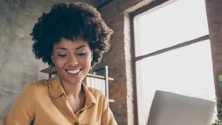 Young woman taking notes during remote meeting