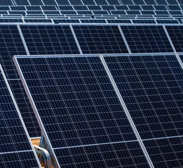 Close-up view of multiple rows of dark blue solar panels with grid patterns, arranged in a solar farm.