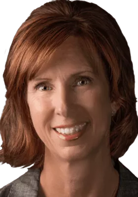 Portrait of a woman with shoulder-length brown hair smiling, wearing a dark blazer.