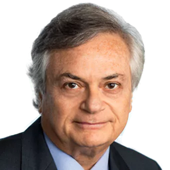 Portrait of an older man with gray hair, wearing a dark suit and blue shirt, against a white background.