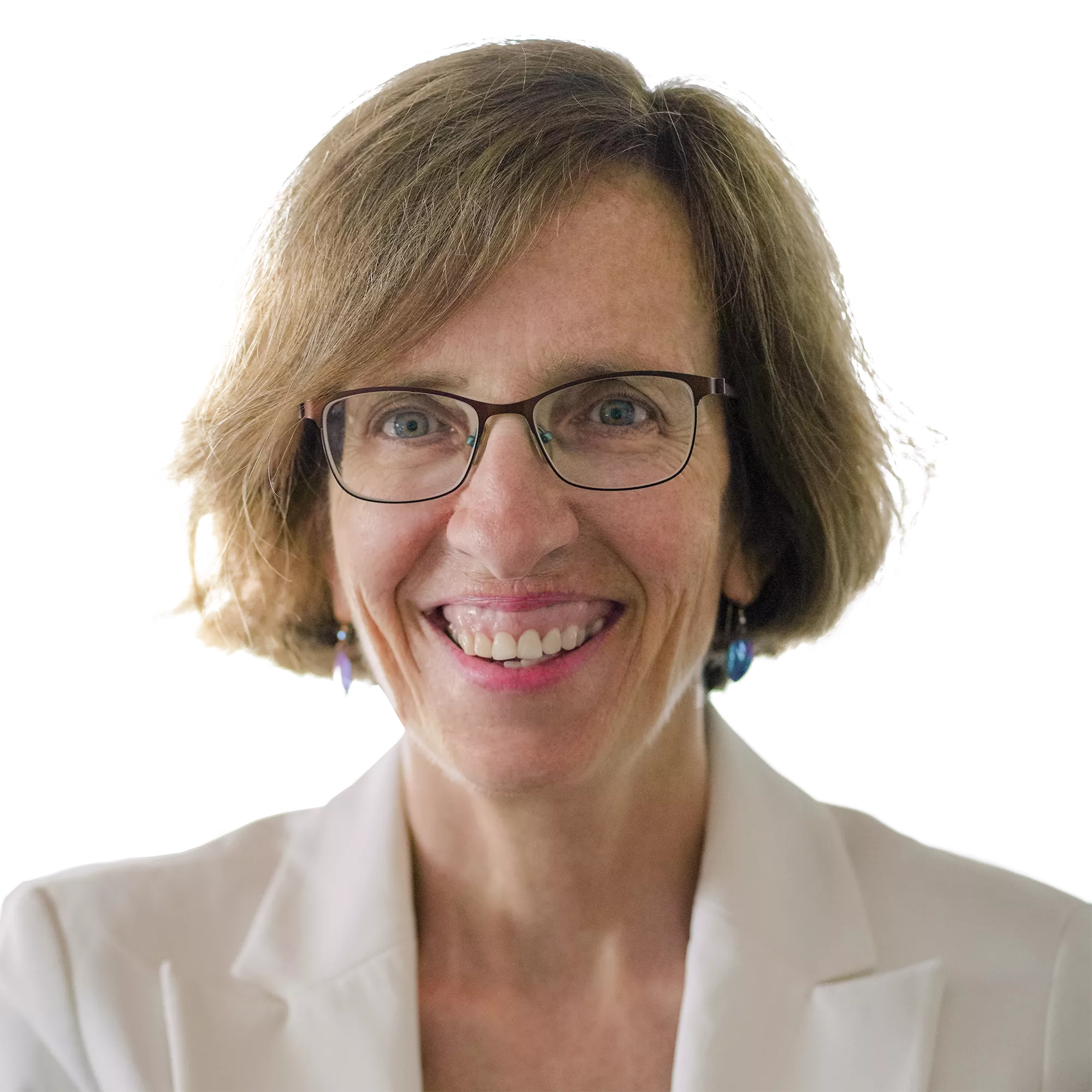 A woman with short brown hair and glasses smiles warmly. She is wearing a white blazer and earrings, with a light background.